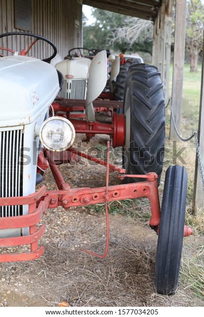 An old tractor sitting\
under a barn.