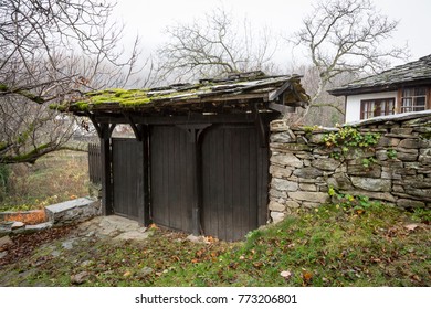 Old traditional Bulgarian house door from the Revival period with stone fence covered of green moss, Bozhentsi, Gabrovo, Bulgaria.