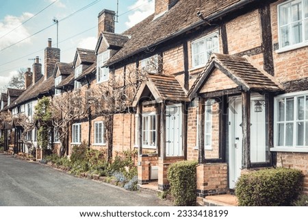 Old traditional English houses in a row. Medieval tudor style with dark beams and brick facade.