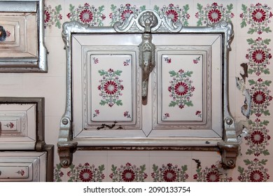 Old Traditional Fireplace, Oven With Ceramic Tiles. Part Of Old Kitchen Oven. Iron Wood Stove With Vintage Tiles. Close Up Of Vintage Oven Door