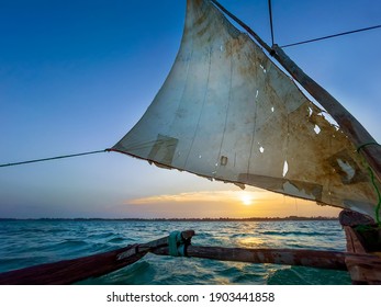 Old traditional maritime traditional vessel Dhow boat sailing under torned sail in the open Indian ocean near Zanzibar island in beautiful sunset, Tanzania. Traveling and unique local culture concept. - Powered by Shutterstock