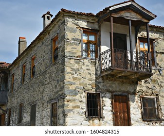Old traditional rural house with stone walls, clay tile rooftop and wooden balcony in Aghios Germanos, Florina West Macedonia, Greece. - Shutterstock ID 1604824315