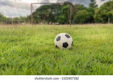 Old Traditional Soccer Ball On Rural Grass Soccer Field With Green Nature