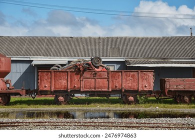 Old train cargo wagons rusting in an industrial yard, car wreck loaded on top