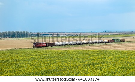 Old train composition passes through the field to a highway in Bulgaria.