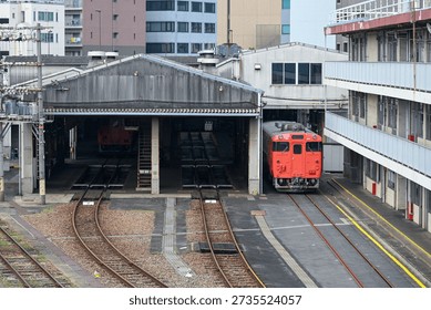 old train depot with two empty tracks in locomotive shed and one with newly painted diesel rail car parked