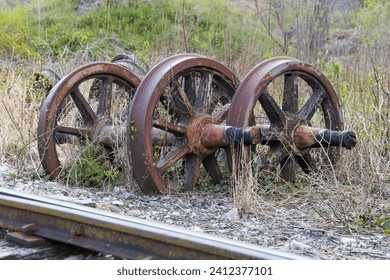 old train wheels rusting beside rails in the grass