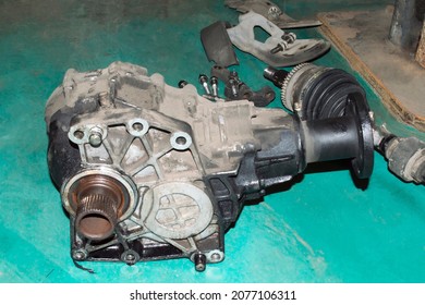 The Old Transfer Case, Removed From The Car, Lies On The Green Floor In The Auto Repair Shop Near The Drive Shaft