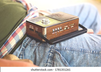 Old Transistor Radio, Brown, Black Laying On The Lap Of A Fat Man Lying There Listening Happily