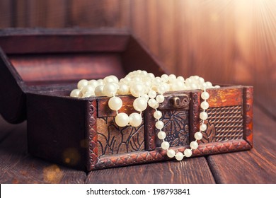 alte Schatztruhe mit Perlenketten auf Holztisch