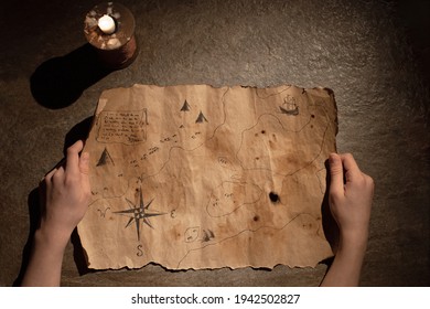 old treasure map in hands  burning candle  concept travel  adventure  search for pirate treasure