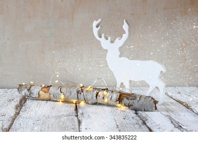 Old Tree Log With Fairy Christmas Lights And Reindeer On Wooden Table.selective Focus.glitter Overlay