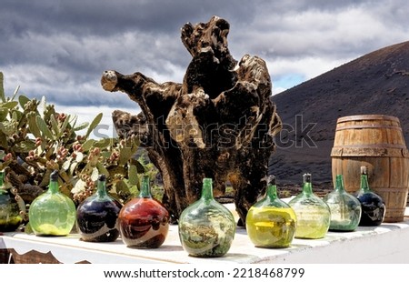 Old tree stump, bottles of wine, and wine barrel outside a Bodega - Lanzarote, Spain