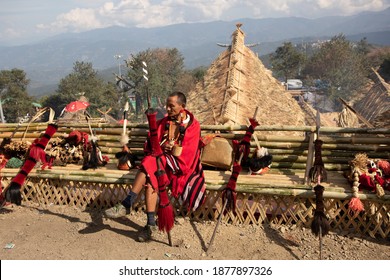 An old tribal warrior from nagaland dressed in traditional attire siting with traditional naga weapons kept by his side in village kisama Nagaland India on 2 December 2016