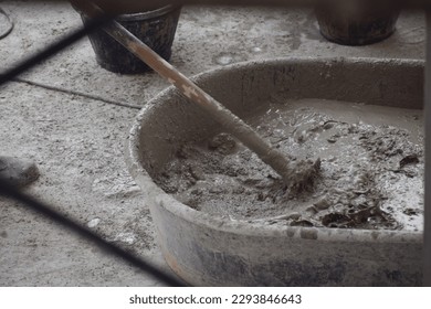 old trowel and bucket with mortar at consturction site,Cement mixed in a mortar mixing bucket for building construction using a hoe as a tool for mixing. Cement mixing concept, manual,selective focus.