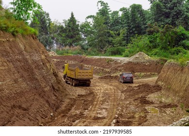 An Old Truck Driving On A Muddy Road Surrounded By Rocks In A Rural Area