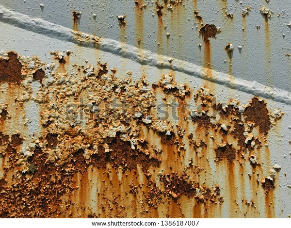 The old truck had paint,\
cracked paint, broken paint and rusted, parked outdoors in the gas\
station.