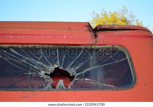 An old truck rear window that is shattered and has\
a hole in it. If only this old truck could talk. What kind of\
stories would it have?