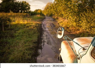 Old Truck Traveling On The Road Among Fields. After The Rain. Puddles And Mud On The Road. Country Road Among The Vineyards