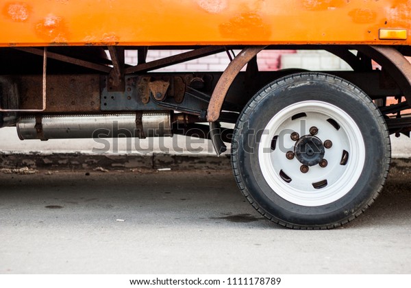 Old truck\'s rear wheel and old rusty parts hiden\
under new painted body