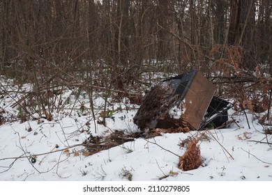 An old TV and an old couch lie in the winter woods on the road. Unusual landscape. Artistic landscape. Photo taken in Gomel, Belarus on January 20, 2022