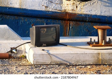 Old TV On The Pier Against The Background Of The Old Rusty Side Of The Ship. Selective Focus.