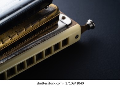 the old two diatonic and one chromatic harmonica, one on top of the other on a dark background. Horizontal orientation.
