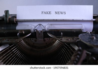 old typewriter on table, words fake news are printed on paper in large size, candle is burning, retro style, concept of information hoax in social media, misleading, exposing deception