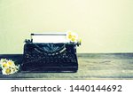 Old typewriter with paper and flowers on table background