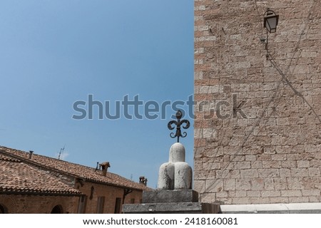 Old typically European brick wall and tiled roof with fleur de lys against blue sky in Gubbio Italy.