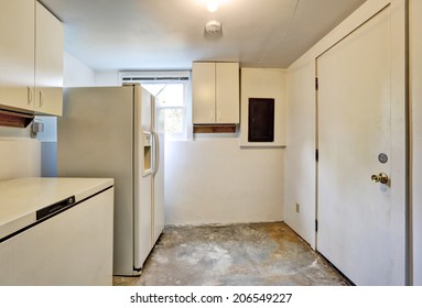 Old Ugly Room In House Basement With White Cabinets, Old Refregirator And Dirty Concrete Floor