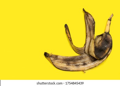 Old Ugly Rotten Spoiled Banana Peel, Over Ripe Fruit Isolated On A Yellow Background, Copy Space.