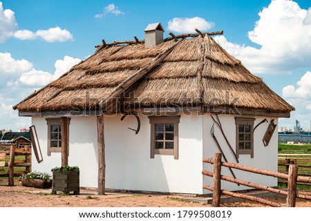 Old Ukrainian hut coated with clay, national traditional house of Slavs with a roof made of reeds or straw