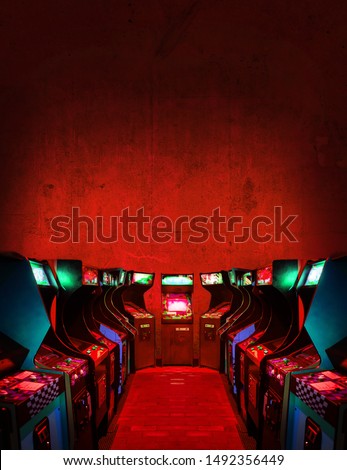 Old Unbranded Vintage Arcade Video Games in a dark gaming room with red light with glowing displays and concrete wall - vertical photo of retro design with free copy space for a poster or magazine