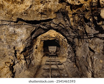 Old underground mine tunnel, mining cart and tracks. Rocky, narrow mine passage - Powered by Shutterstock