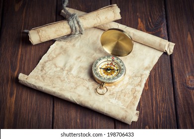 Old Unrolled Map, Rolled Map And Compass On Wooden Table