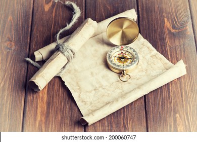 Old Unrolled Map, Rolled Map And Compass On Wooden Table