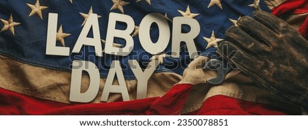 Old US American flag with a worn work glove holding a crescent wrench with Labor day text. Labor day and American blue collar worker concept.