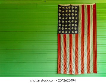 Old USA flag with 48 stars on an old green school room wall.