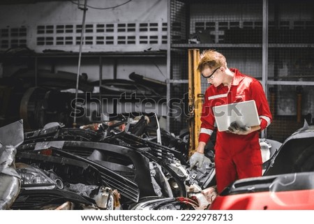 Old used car part warehouse worker checking inventory in garage. Staff worker working in recycle motor junkyard auto parts management.