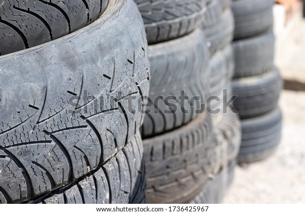 Old\
used car tires stacked on top of each other near the tire shop.\
Selective focus. Closeup view. Blurred\
background