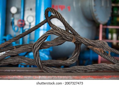 Old Used Crashed (breaking) Steel Cable With Some Cotton Threads. Very Dangerous To Use. Blue Electric Machine On Background, Blurred. Abstract Industrial Close-up Photo.