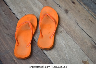 old used orange flip-flops on wooden floor