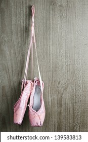 Old Used Pink Ballet Shoes Hanging On Wooden Background