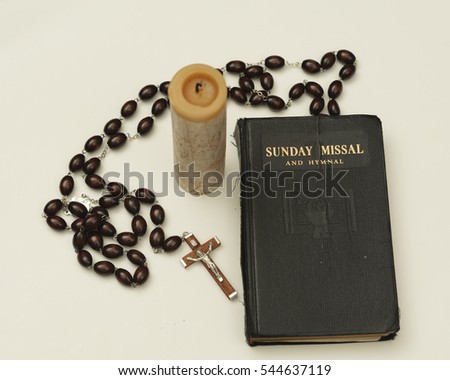 Old and used Sunday Missal with  rosary and candle