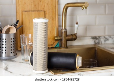 Old used tap water filter cartridges on the kitchen countertop near the sink. Clean water concept for drinking and cooking