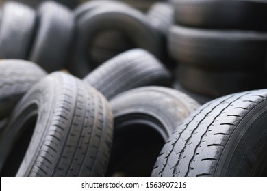 Old used tires stacked with high piles. close up damaged worn black tire tread car. tread problems and solutions for road safety concept. Change time. transportation.  