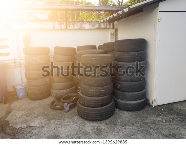 Old used tires stacked\
with high piles in secondary car parts shop garage. Bunch of old\
tires from used cars. Environmental pollution. Dump tires.\
Industrial background.