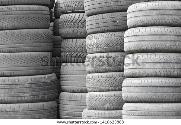 Old used tires stacked with high piles in\
secondary car parts shop\
garage