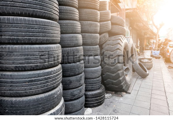Old used tires stacked with high piles beside the\
tire shop.